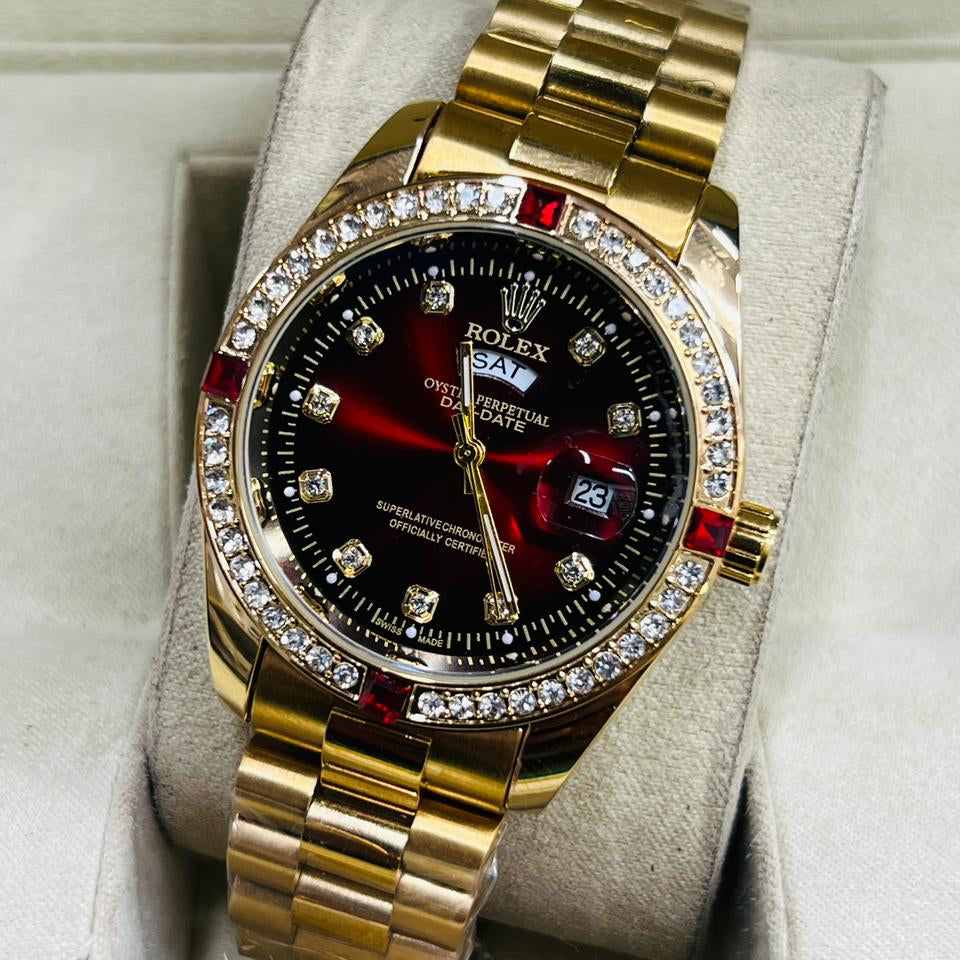 Luxury gold watch with a black face and red accents, displayed in a box.